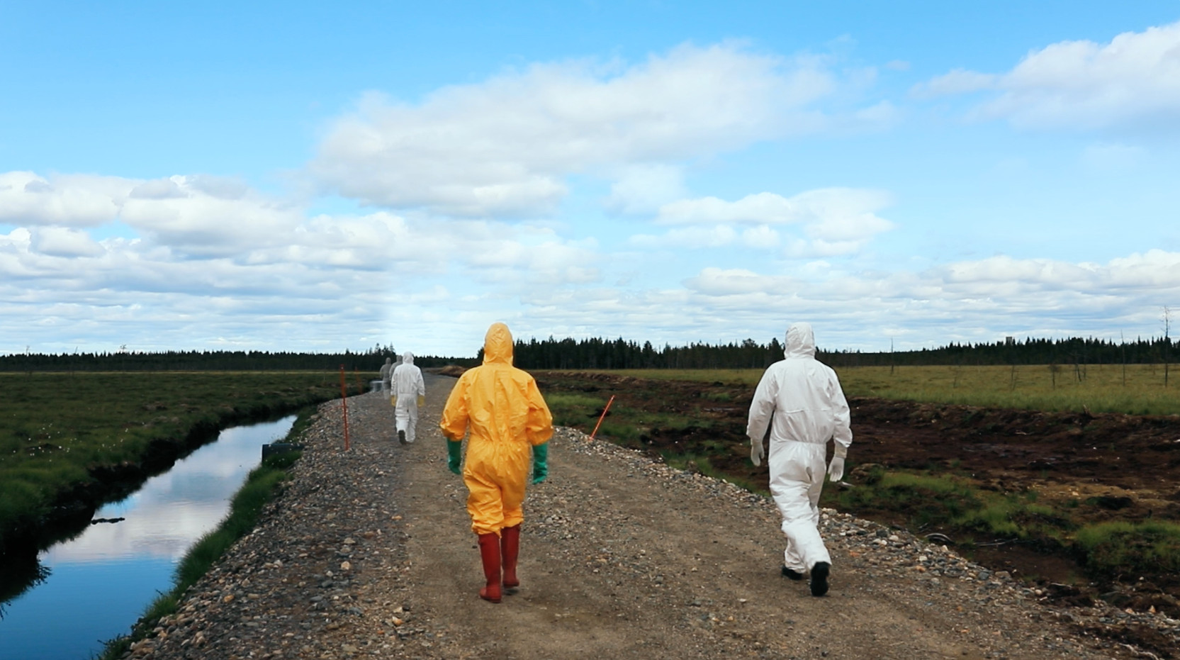 Persons in protective suits walking in a landscape